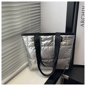 Detail of silver metallic quilted tote bag with square stitching and black fabric straps