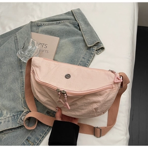 Detail of pink half-moon crossbody bag made of lightweight pleated nylon fabric