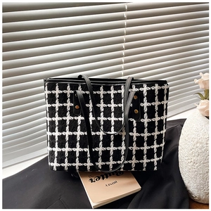 Detail of checkered tweed tote bag featuring black faux leather straps and gold rivets