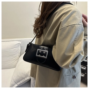 Close-up of a black leather underarm bag with a large silver buckle worn with a beige coat