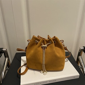 Brown frosted suede bucket bag with gold chain drawstring and pearl detail on books