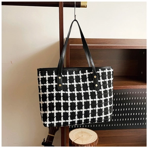 Detail of tweed striped tote bag with black straps and golden metal rivets close-up