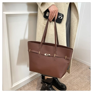 Detail of a vintage dark brown leather tote bag with a golden metal twist lock closure