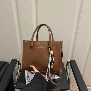 Brown high-gloss PU leather tote bag with stylish charms and adjustable shoulder strap