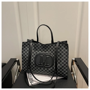 Detail of jacquard tote bag featuring all-over M monogram pattern and large embossed M logo