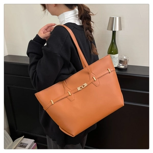 Close-up of caramel leather tote bag with gold metal buckle on female shoulder