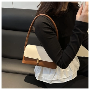 Detail of minimalist shoulder bag featuring contrasting cream flap and brown leather base