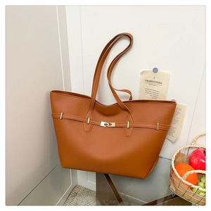 Detail of caramel leather tote bag featuring a vintage belt buckle and gold hardware