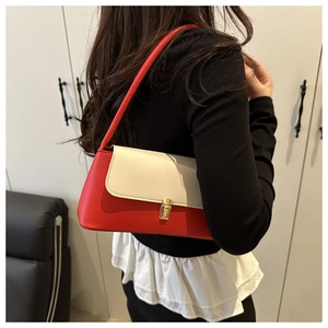 Detail view of red and beige contrast shoulder bag with a gold metal lock and long strap