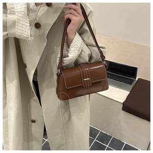 Detail der braunen Baguette-Tasche im Vintage-Stil mit weißen Nähten und Schnallenverschluss