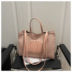 Pink tote bag detail with letter M monogram print and embossed logo on leather surface
