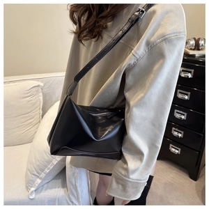 Dettaglio di una borsa a tracolla minimalista in ecopelle nera indossata da una modella