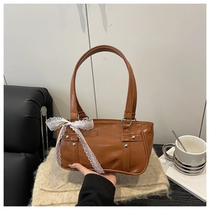 Brown faux leather Boston bag featuring silver studs and a white lace bow detail