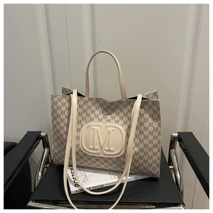Detail of cream tote bag featuring embossed M logo and monogram print on leather texture