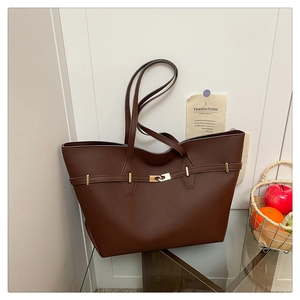 Detailed close-up of dark brown tote bag featuring golden metal lock and fine leather texture