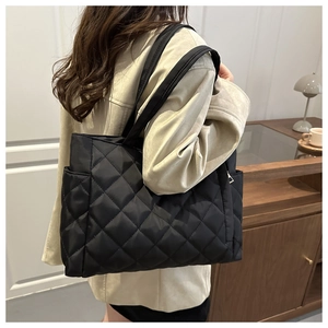 Detail of black quilted tote bag showing diamond stitching and side pocket storage