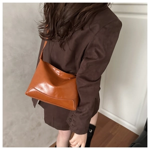 Dettaglio della borsa a tracolla in pelle marrone caramello su modella con design retrò