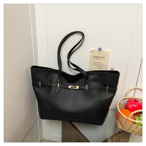 Detail of black faux leather tote bag with gold buckle strap in a lifestyle setting