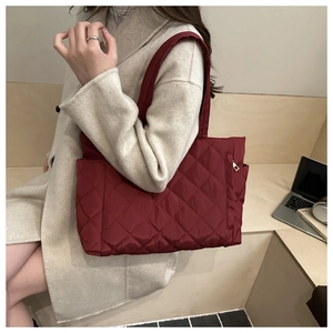 Close-up of quilted burgundy tote bag with large diamond stitching and side zipper pocket