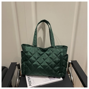 Detail of dark green quilted tote bag with diamond stitching and side pocket storage