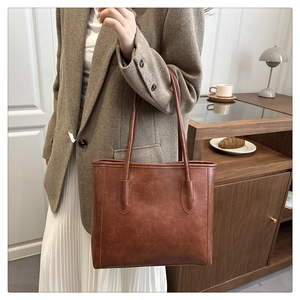 Close-up of brown vintage tote bag worn over the shoulder with soft textured leather finish