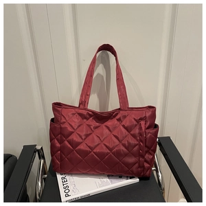 Close-up of wine red quilted tote bag with diamond stitching on a leather chair