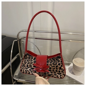 Détail du sac à bandoulière léopard avec un nœud en cuir verni rouge et une bandoulière fixe