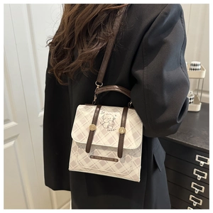 Détail du sac bandoulière à carreaux avec illustration de chien et lanières en cuir