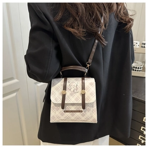 Détail du sac à main à carreaux avec illustration de chien et bandoulière en cuir