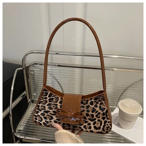 Détail du sac sous le bras en fausse fourrure léopard avec un nœud décoratif en cuir verni