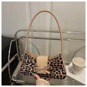 Gros plan d'un sac bandoulière léopard avec détail de nœud en cuir verni beige exposé