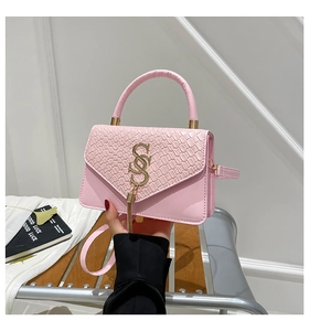 Detail of pink croc-embossed leather bag with golden SS logo and tassel charm detail
