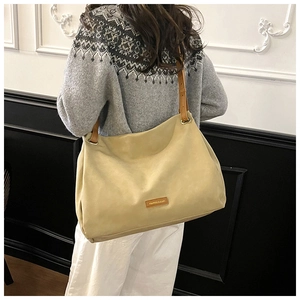 Detail of minimalist beige suede tote bag with brown leather straps and metal eyelets