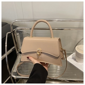 Détail du sac beige avec fermoir rotatif doré et poignée supérieure en cuir élégante