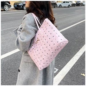Sac fourre-tout rose avec motifs nœuds noirs et breloque dorée en décor extérieur