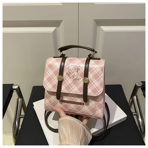 Détail d'un sac à dos à carreaux roses avec imprimé chiot et plaque de logo dorée