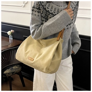 Detail of khaki suede hobo bag with brown leather strap and brand logo patch