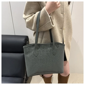 Detail of leopard print tote bag shoulder strap shown with elegant wool coat
