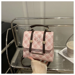 Gros plan sur un sac à main à carreaux roses avec illustration de chien et logo en métal