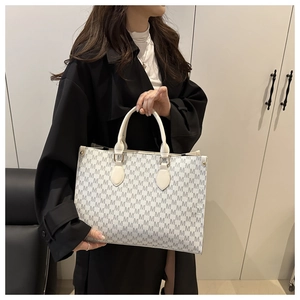 Detailed view of large tote bag with white and grey M letter pattern and gold hardware