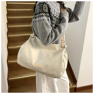 Detail of a large cream leather tote bag with gold metal hardware and brown straps