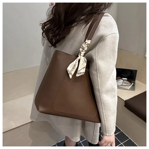 Close-up of brown tote bag with decorative silk scarf on handle in office setting