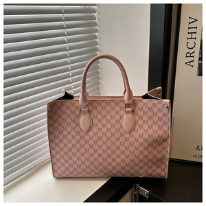 Détail du sac cabas rose avec motif monogramme lettre M et poignée en cuir sur un rebord