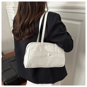 Detail view of white leather shoulder bag with decorative buckle pocket and double straps