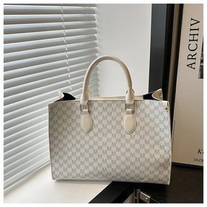 Détail du sac cabas crème avec motif de lettres M grises et boucles en métal doré