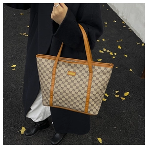Outdoor shot of a beige tote bag with rhombus pattern and brown straps on ginkgo leaves