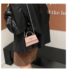 Detail showing pink faux leather crocodile texture and gold clasp on a micro bag