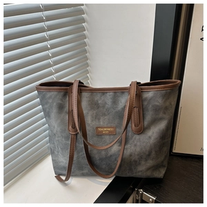 Close-up of grey canvas tote with brown leather handles and vintage brand patch detail