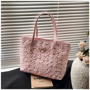 Détail du sac cabas plissé rose avec motifs nœuds noirs et ornement nœud doré en métal