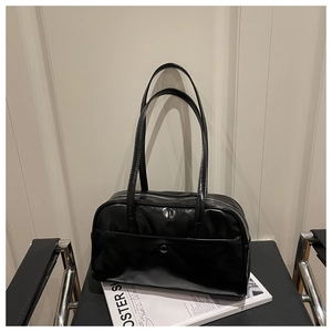 Close-up of black glossy leather handbag with double handles on minimalist background